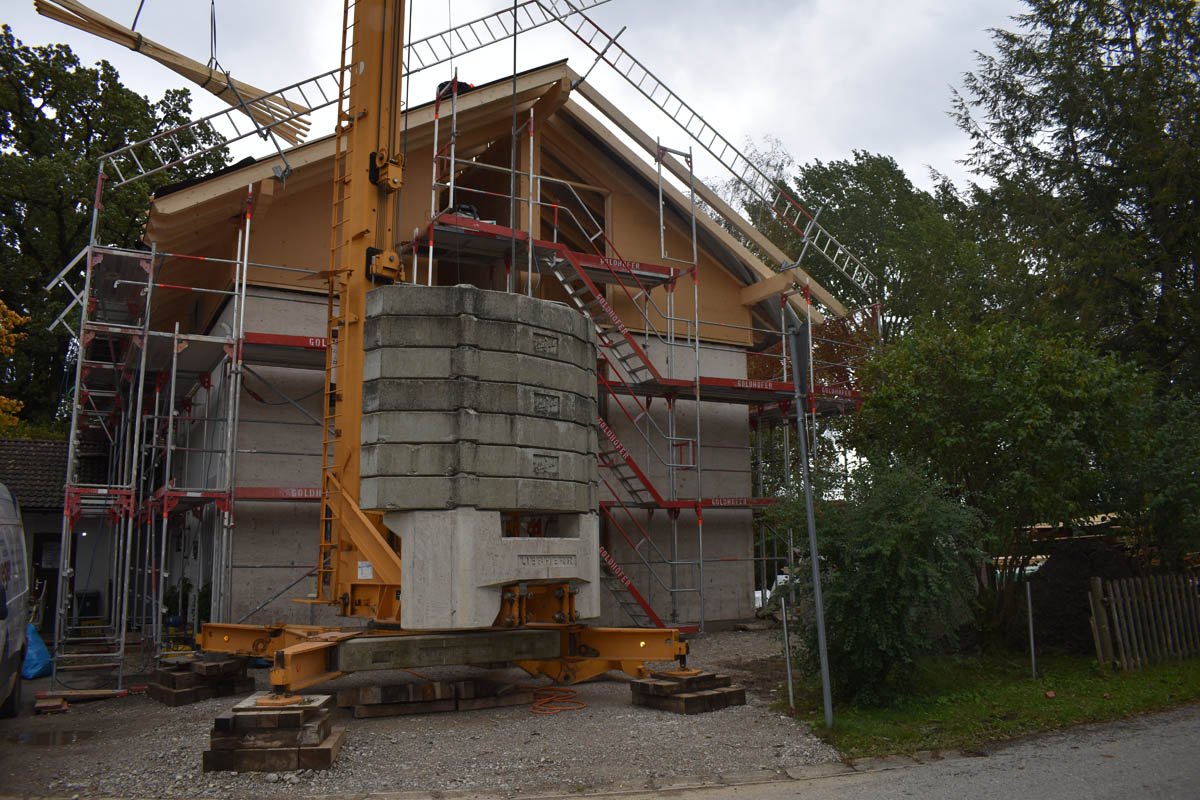 Haus im Rohbau mit Gerüst und Kran im Vordergrund an einer Baustelle.