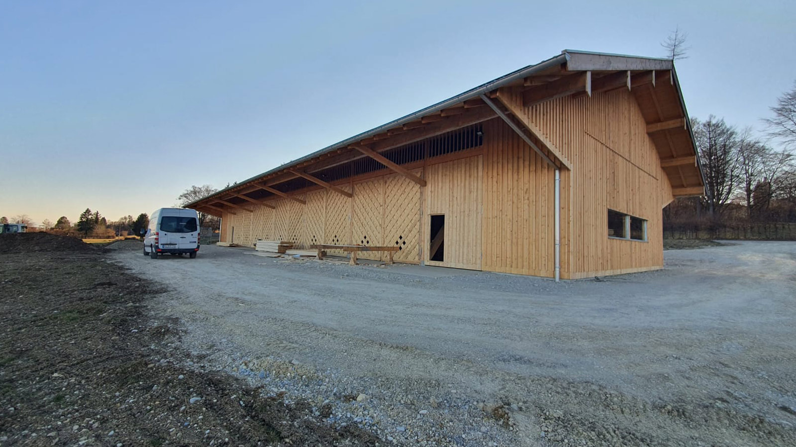 Große Halle mit Holzverkleidung, seitlich aufgenommen, Lieferwagen davor.