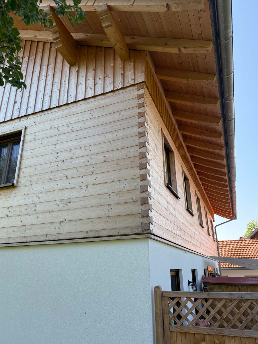 Hausfassade mit Holzverschalung und weißem Sockel