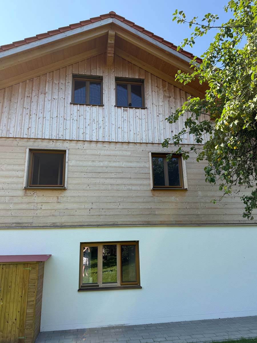 Holzfassade mit mehreren Fenstern an Giebelseite