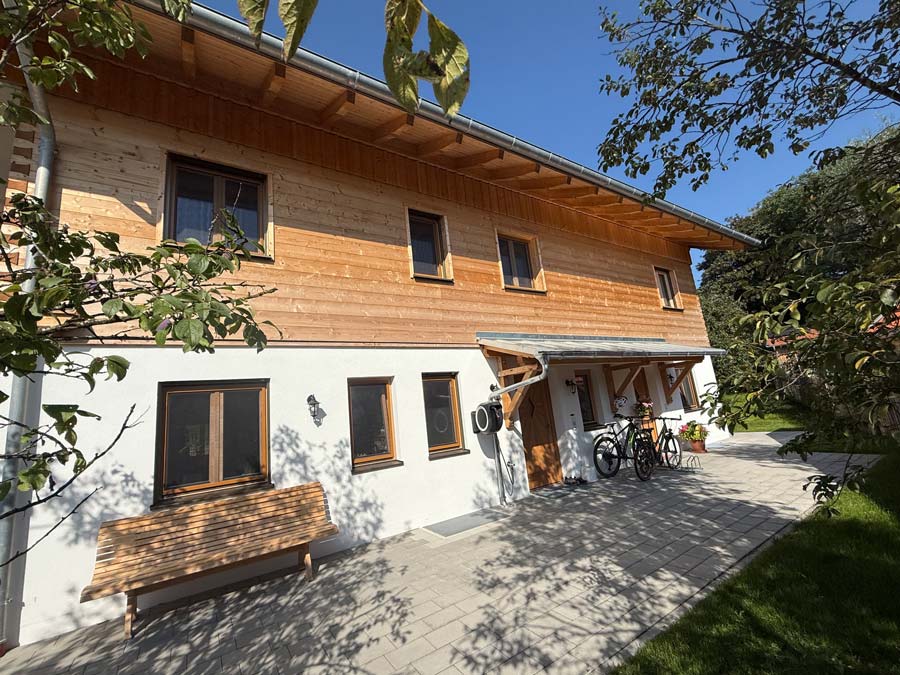 Hausfront mit Holzverschalung und Sitzbank im Garten