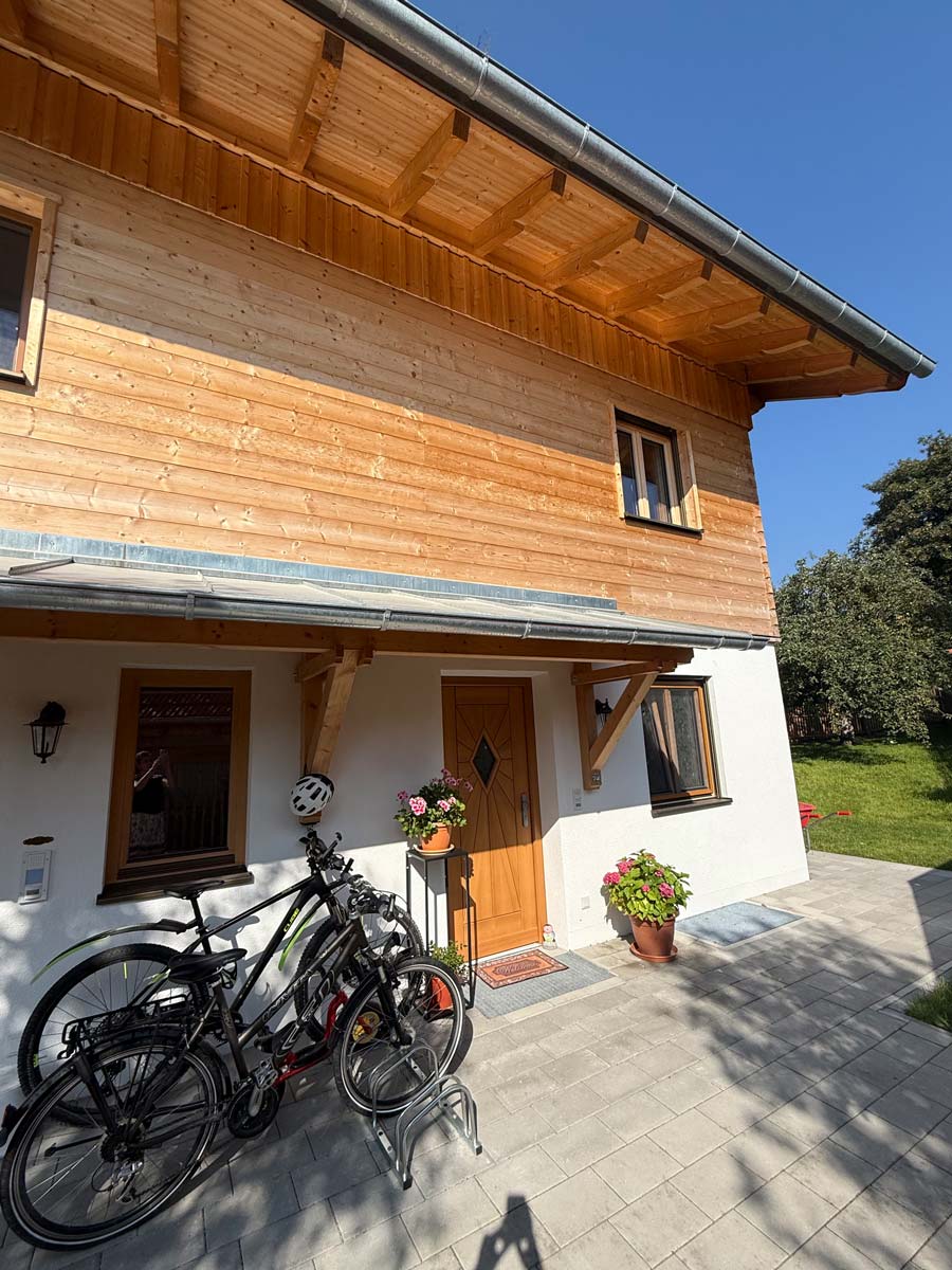 Eingangsbereich mit Holztür, Blumen und Fahrrädern