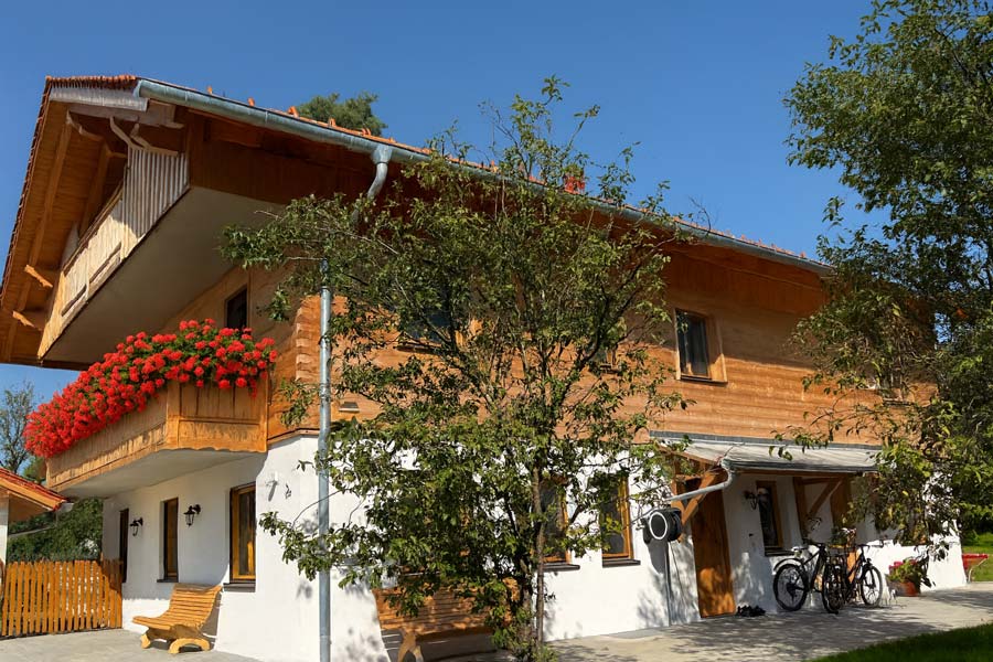 Wohnhaus mit Balkon, Holzfassade und roten Blumen