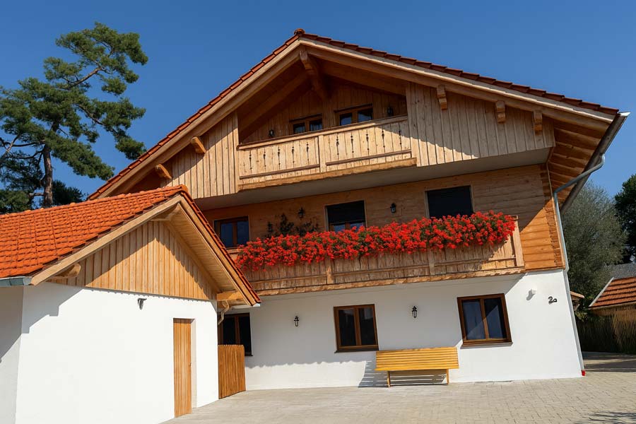 Wohnhaus mit Balkon und roten Blumen vor Garage