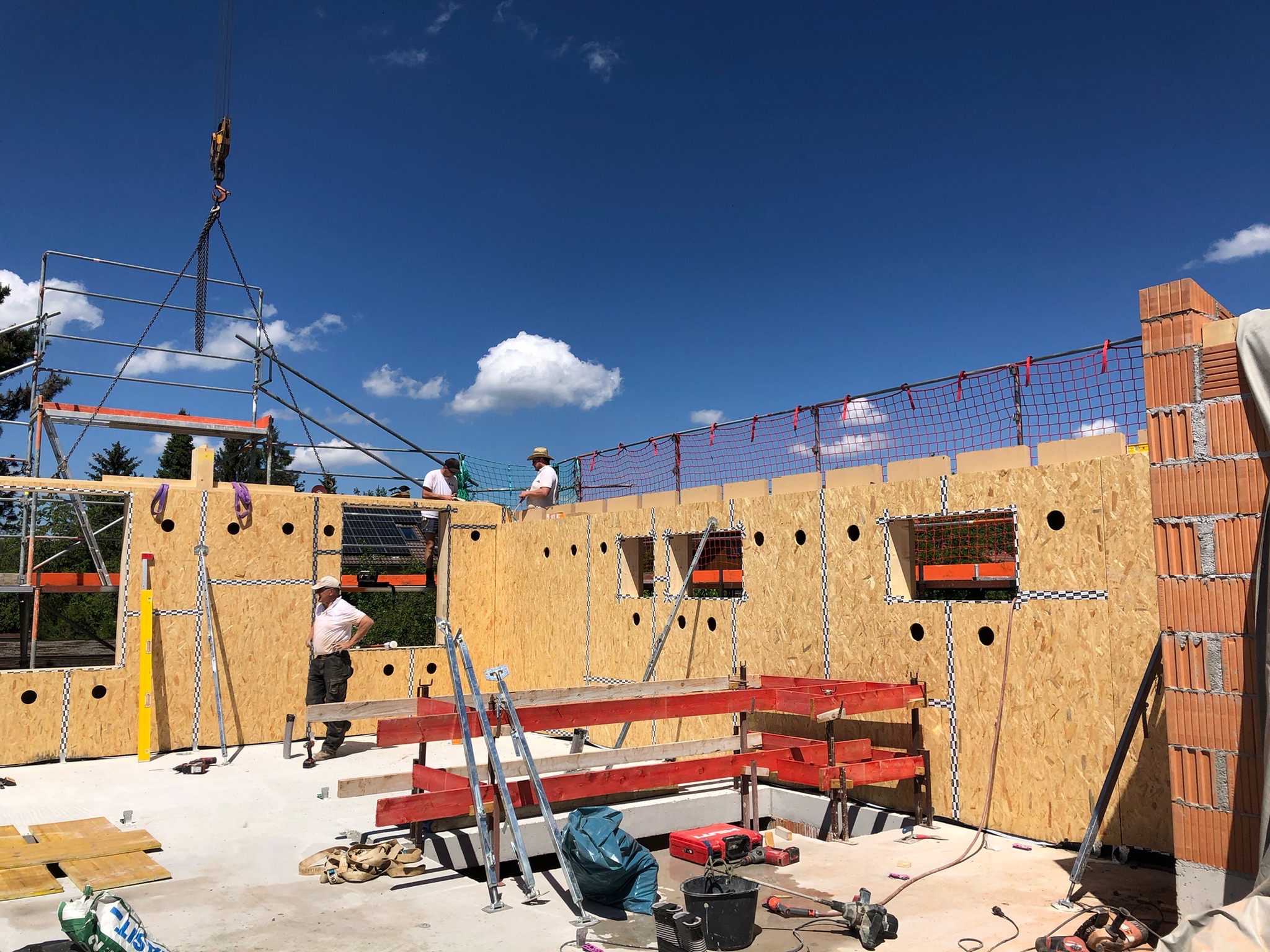 Rohbau eines Holzhauses: Zimmerer montieren vorgefertigte Holzwände mit Kran