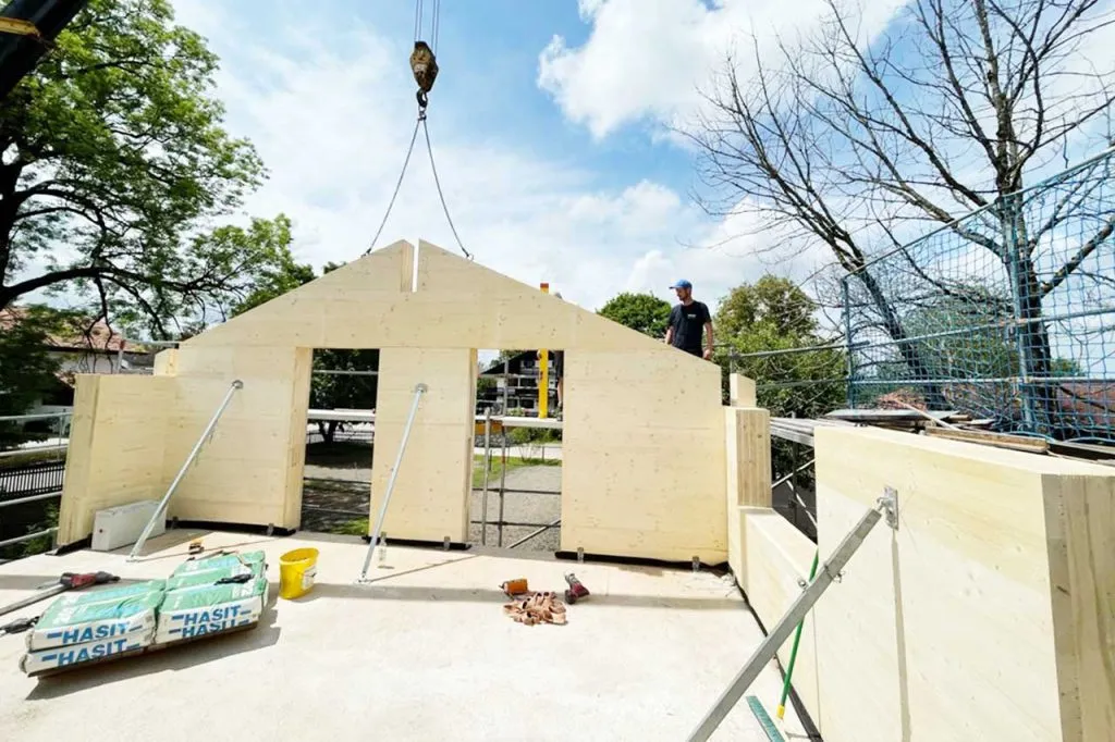 Baustellenfoto der Aufstockung einer Garage, Seitenwand wird mit Hilfe eines Krans platziert