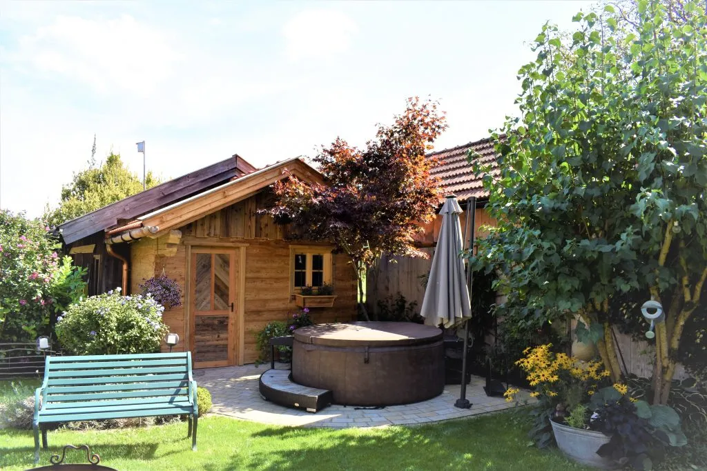 Frontansicht eines Gartenhauses aus Holz img Garten mit Whirlpool und Sitzbank