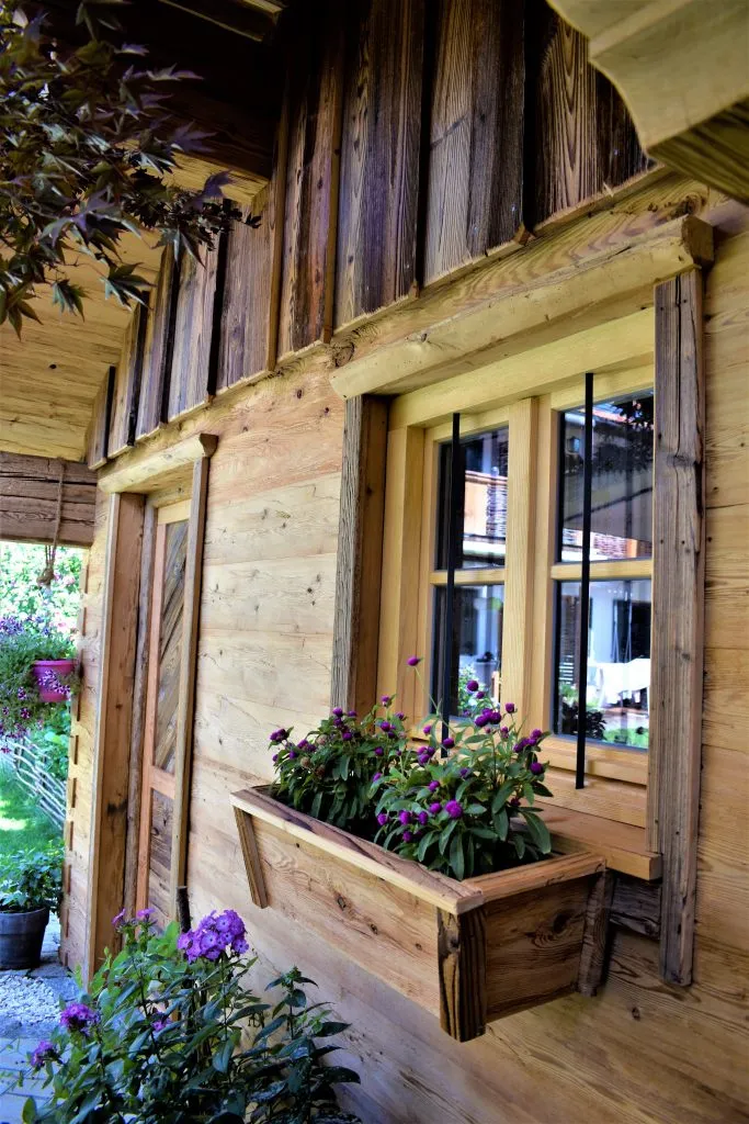 Nahaufnahme eines Gartenhauses aus Holz, Fenster mit Blumenkübel davor